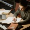 資格勉強・受験勉強で参考書に向かい集中して書き込みをする学習者の机の様子