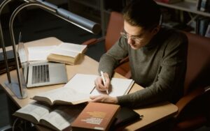資格勉強・受験勉強で参考書に向かい集中して書き込みをする学習者の机の様子