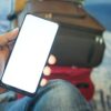 空港でスマートフォンを手にする旅行者（海外旅行の通訳アプリのイメージ）