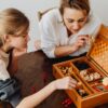 テーブルでボードゲームの箱を開けて一緒に遊ぶ母親と娘