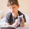 家で本を音読する小学生の男の子
