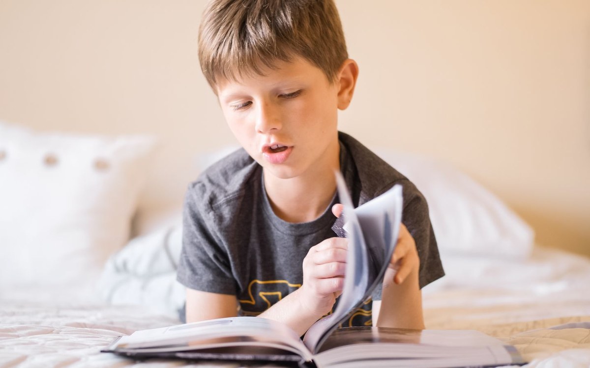 家で本を音読する小学生の男の子