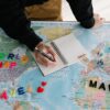 世界地図の上でノートに書き込みながら次に学ぶ言語と旅行先を考える様子