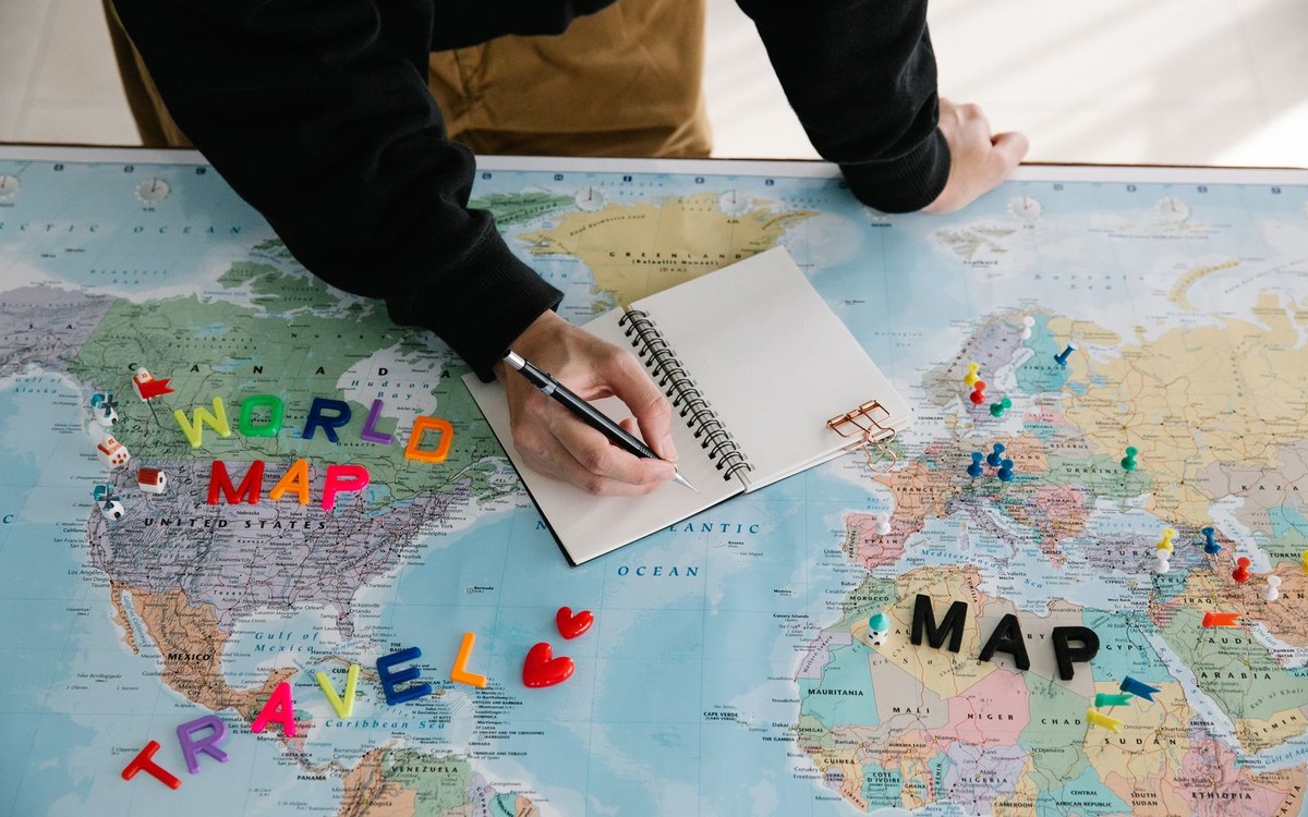 世界地図の上でノートに書き込みながら次に学ぶ言語と旅行先を考える様子