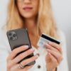 スマホとクレジットカードを手に持ちネットショッピングをする女性