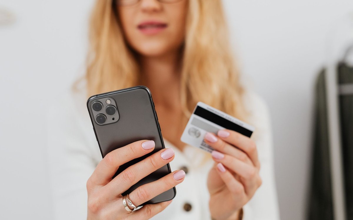 スマホとクレジットカードを手に持ちネットショッピングをする女性