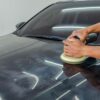 ダブルアクションポリッシャーを両手で持ち黒い車のボンネットを磨く様子